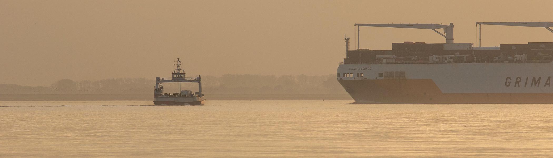 Containerschiff und Elbfähre im Sonnenuntergang